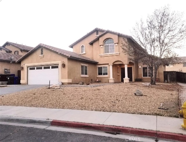 mediterranean / spanish house featuring concrete driveway, an attached garage, a tile roof, and stucco siding