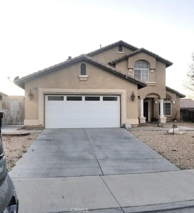 view of front of home with a garage, concrete driveway, a tiled roof, fence, and stucco siding