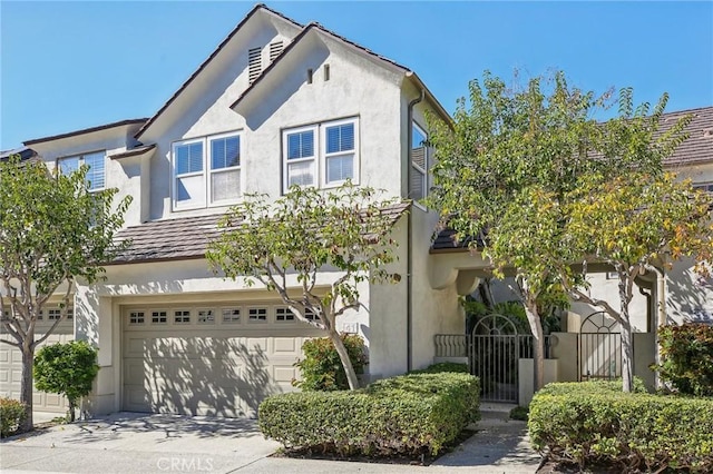 view of front facade with driveway, a garage, a gate, and stucco siding