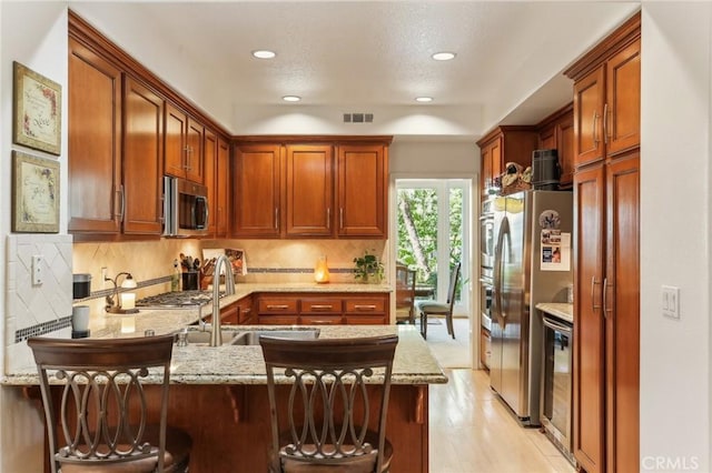 kitchen with beverage cooler, visible vents, a peninsula, stainless steel appliances, and a sink