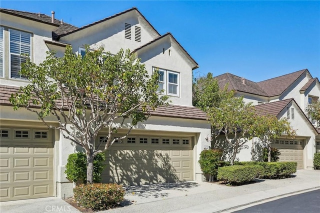 view of front of property with concrete driveway, an attached garage, and stucco siding