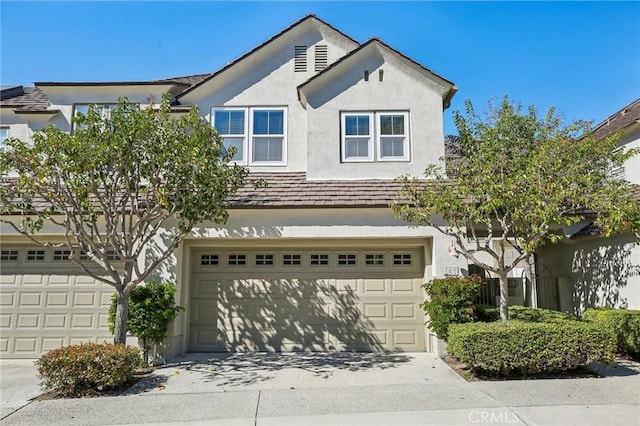 view of front facade featuring a garage, concrete driveway, and stucco siding