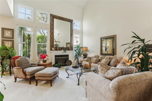 living area with carpet floors, a glass covered fireplace, and a towering ceiling