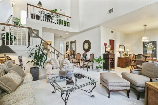 carpeted living room featuring a high ceiling, stairway, and visible vents