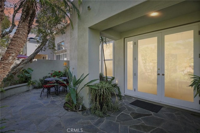 exterior entry at dusk featuring a patio area, stucco siding, and french doors