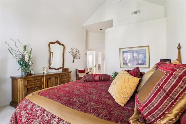 carpeted bedroom featuring high vaulted ceiling and visible vents