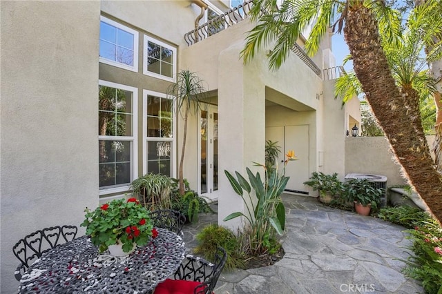 view of exterior entry with central AC and stucco siding