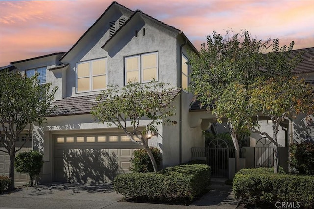 view of front facade featuring driveway, an attached garage, and stucco siding