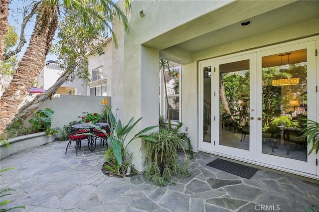 view of exterior entry with french doors, a patio area, and stucco siding