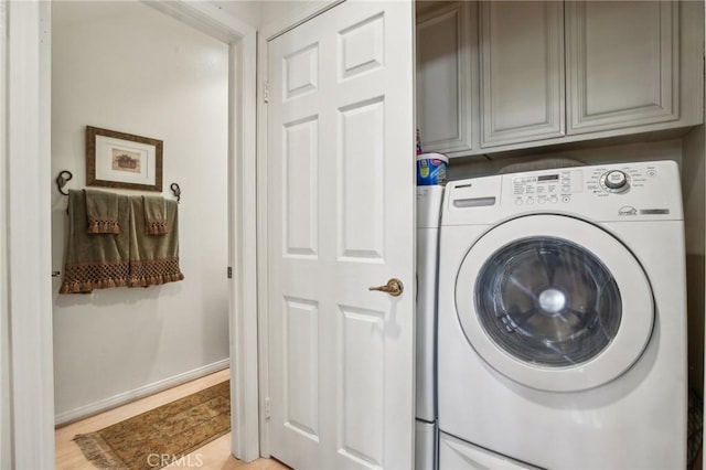 washroom with washer / dryer, baseboards, light wood-style floors, and cabinet space