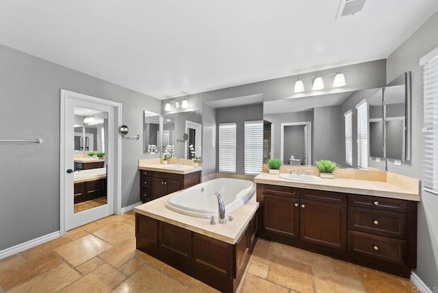 full bathroom with stone tile floors, a sink, and a wealth of natural light