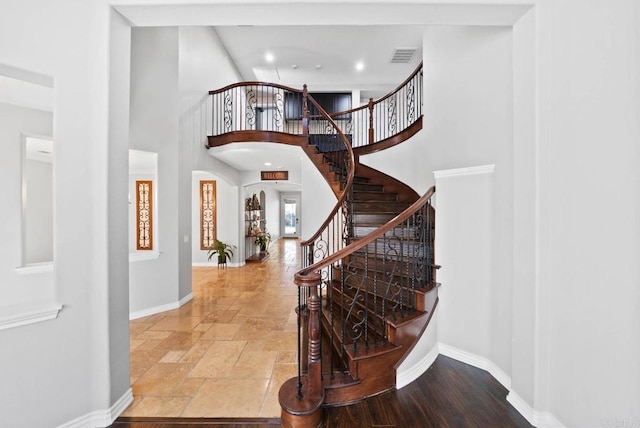 entryway with visible vents, baseboards, a high ceiling, stone tile floors, and stairs