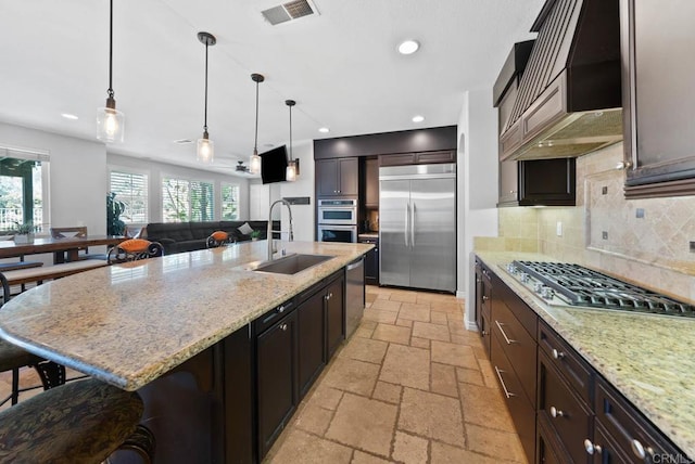 kitchen featuring stone tile floors, visible vents, custom exhaust hood, a sink, and stainless steel appliances