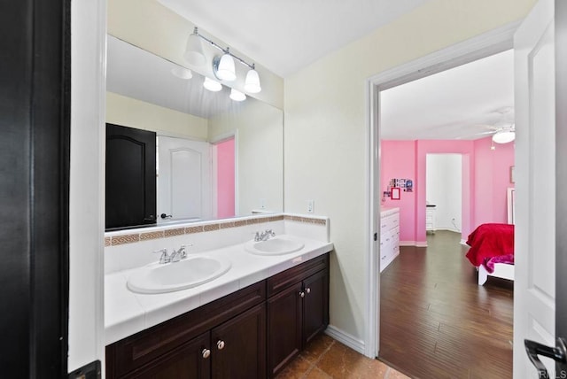 full bath with double vanity, a sink, baseboards, and ensuite bath