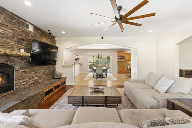 living room with visible vents, arched walkways, ceiling fan, light wood-style floors, and recessed lighting