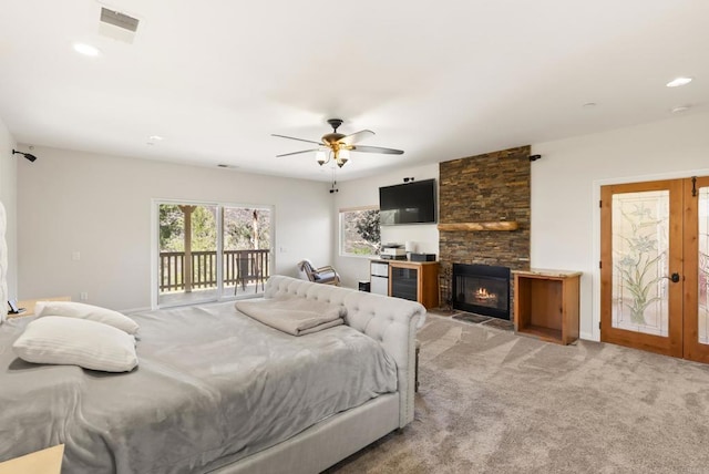 carpeted bedroom with wine cooler, french doors, visible vents, a stone fireplace, and access to outside