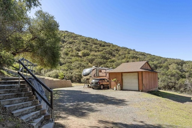 exterior space with driveway, a view of trees, and stairs