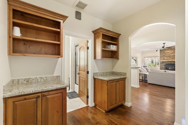 kitchen featuring visible vents, brown cabinetry, a ceiling fan, dark wood-style floors, and open shelves