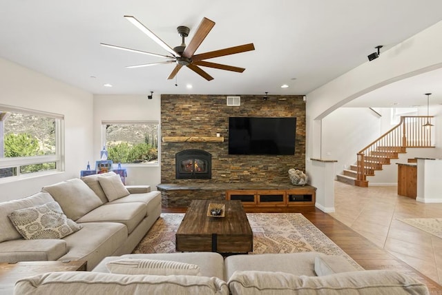 living room featuring baseboards, a ceiling fan, stairway, wood finished floors, and a fireplace