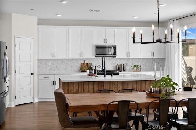 kitchen with appliances with stainless steel finishes, light countertops, visible vents, and white cabinetry