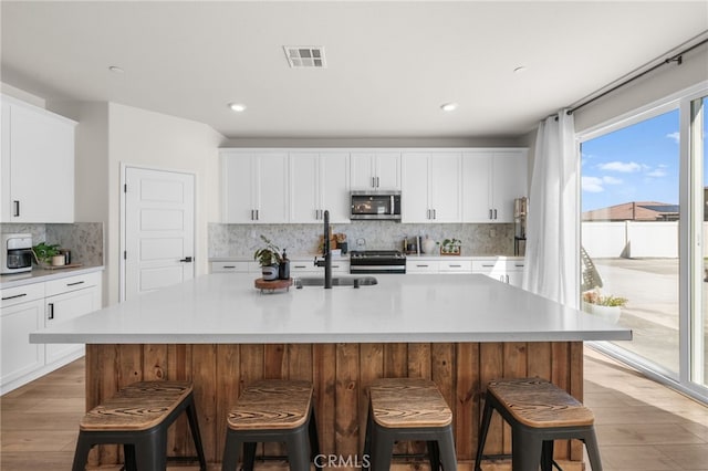 kitchen with stainless steel appliances, light countertops, visible vents, and light wood-style floors