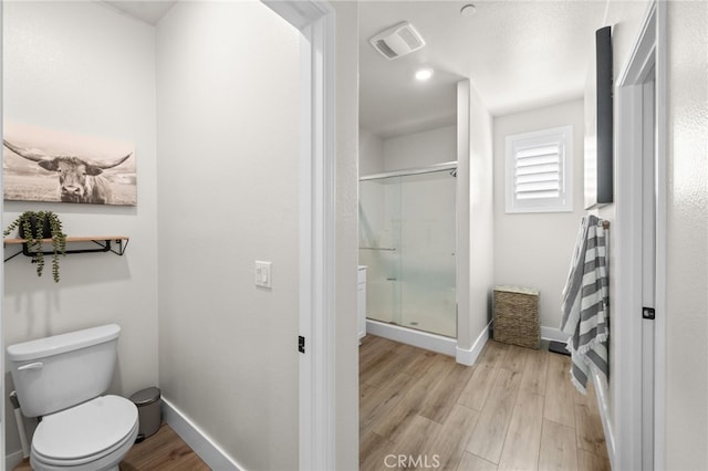 bathroom featuring baseboards, visible vents, toilet, wood finished floors, and a shower stall