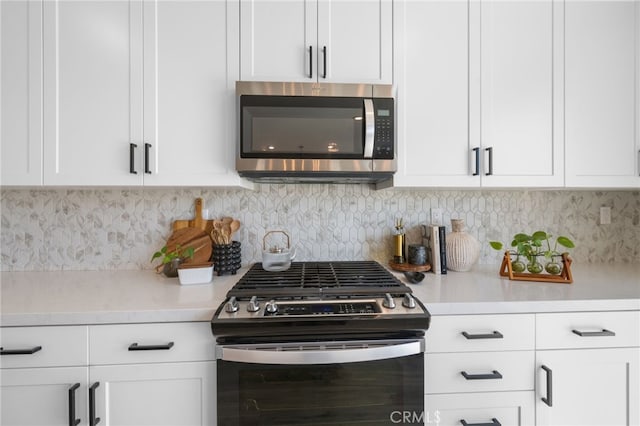 kitchen featuring appliances with stainless steel finishes, white cabinets, light countertops, and decorative backsplash