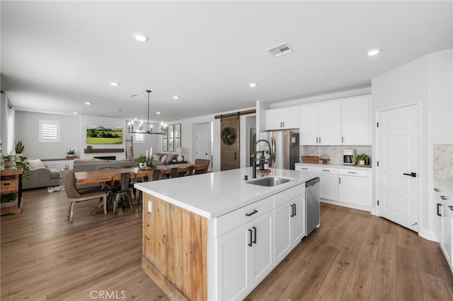 kitchen featuring a barn door, stainless steel appliances, a sink, visible vents, and open floor plan