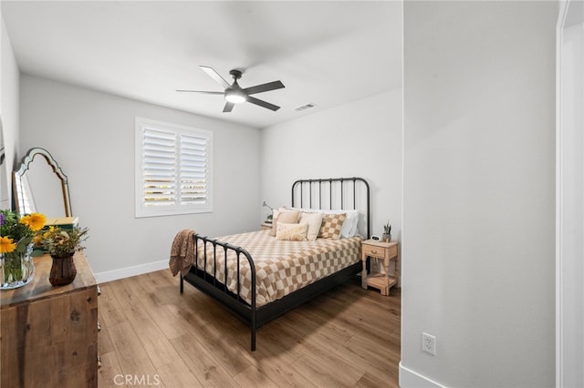 bedroom with light wood-style flooring, a ceiling fan, visible vents, and baseboards