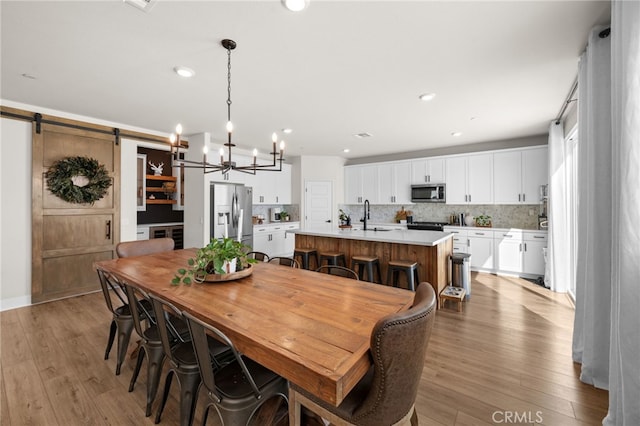 dining area featuring a barn door, an inviting chandelier, hardwood / wood-style flooring, and recessed lighting