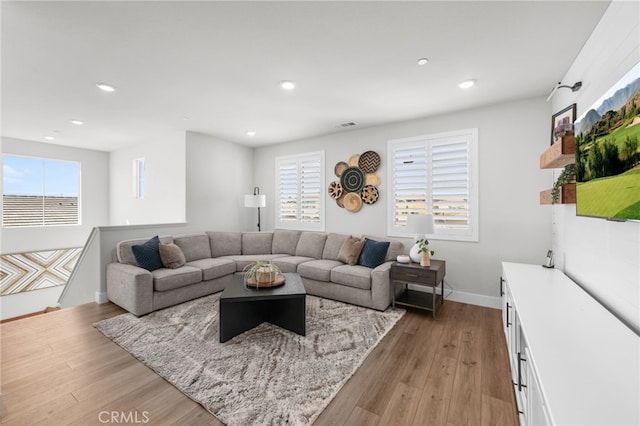 living room with light wood finished floors, baseboards, visible vents, and recessed lighting