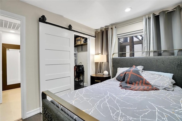 bedroom with baseboards, a barn door, a closet, and recessed lighting