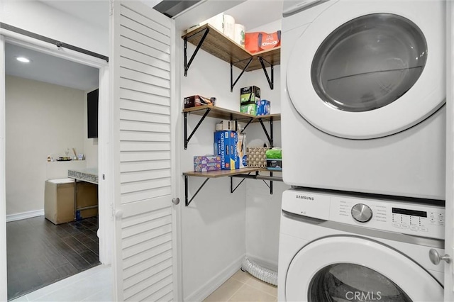 washroom with stacked washing maching and dryer, baseboards, laundry area, and tile patterned flooring