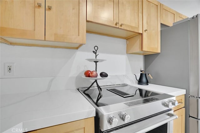 kitchen featuring light countertops, electric range, and light brown cabinets