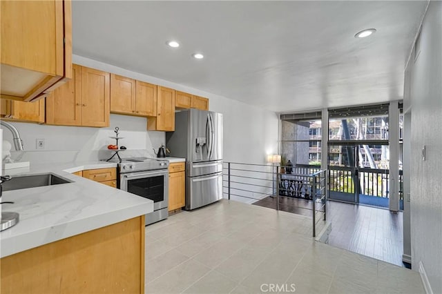 kitchen featuring a sink, recessed lighting, stainless steel appliances, a wall of windows, and light stone countertops