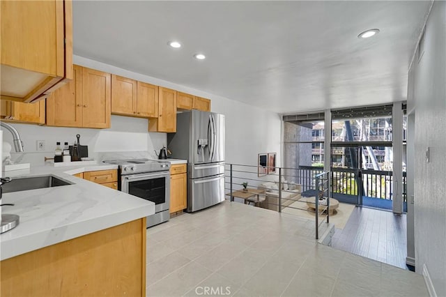 kitchen with a wall of windows, light stone counters, recessed lighting, stainless steel appliances, and a sink