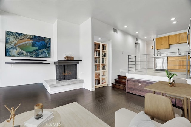 living area featuring a multi sided fireplace, visible vents, recessed lighting, and dark wood-type flooring