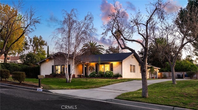 view of front of house with fence, a yard, driveway, and stucco siding