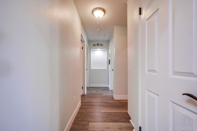 corridor featuring baseboards and wood finished floors