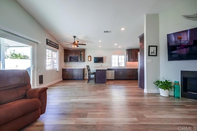 living area featuring light wood-style floors, a fireplace, visible vents, and a wealth of natural light