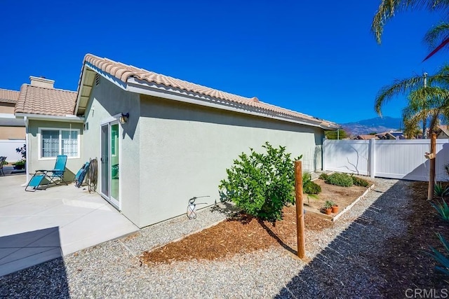 view of home's exterior with a patio, a tile roof, fence, and stucco siding