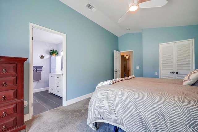 carpeted bedroom with a closet, visible vents, connected bathroom, vaulted ceiling, and baseboards