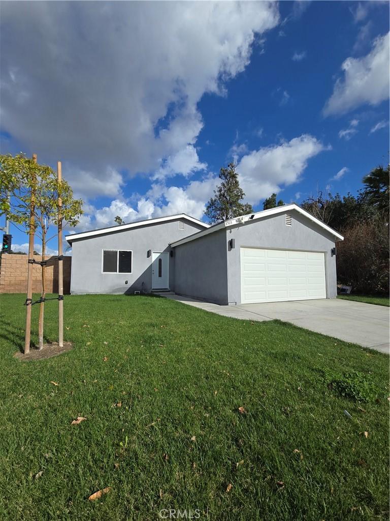 view of front facade featuring driveway, a garage, a front lawn, and stucco siding