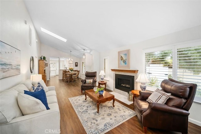 living room with lofted ceiling with skylight, a fireplace, and dark wood finished floors