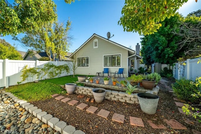 back of house with a patio area, a fenced backyard, a chimney, and a lawn