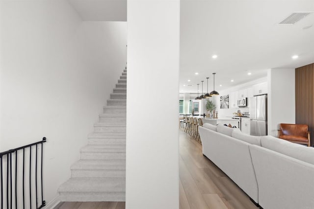 staircase with visible vents, wood finished floors, and recessed lighting