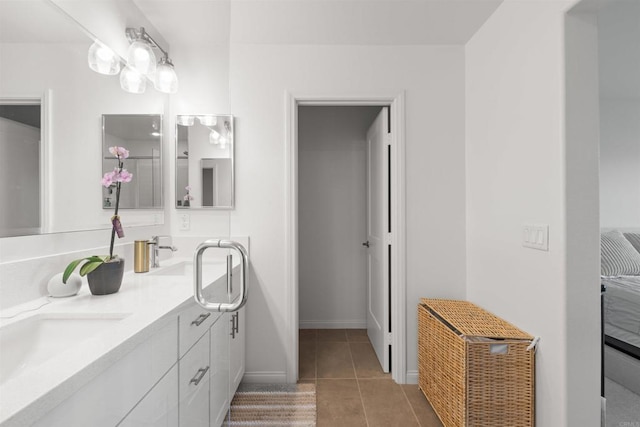 full bathroom with double vanity, tile patterned flooring, baseboards, and a sink