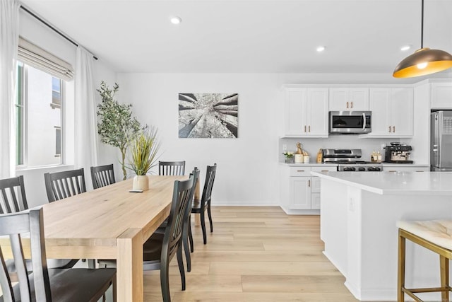 kitchen with light wood-type flooring, white cabinets, stainless steel appliances, and light countertops