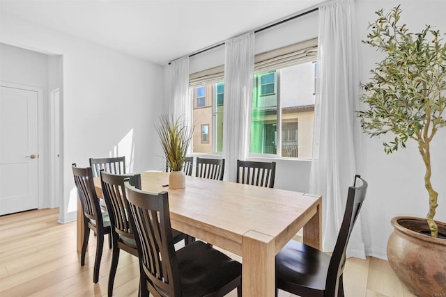 dining area featuring light wood-style flooring and baseboards