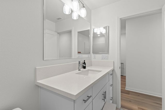 bathroom featuring visible vents, vanity, baseboards, and wood finished floors